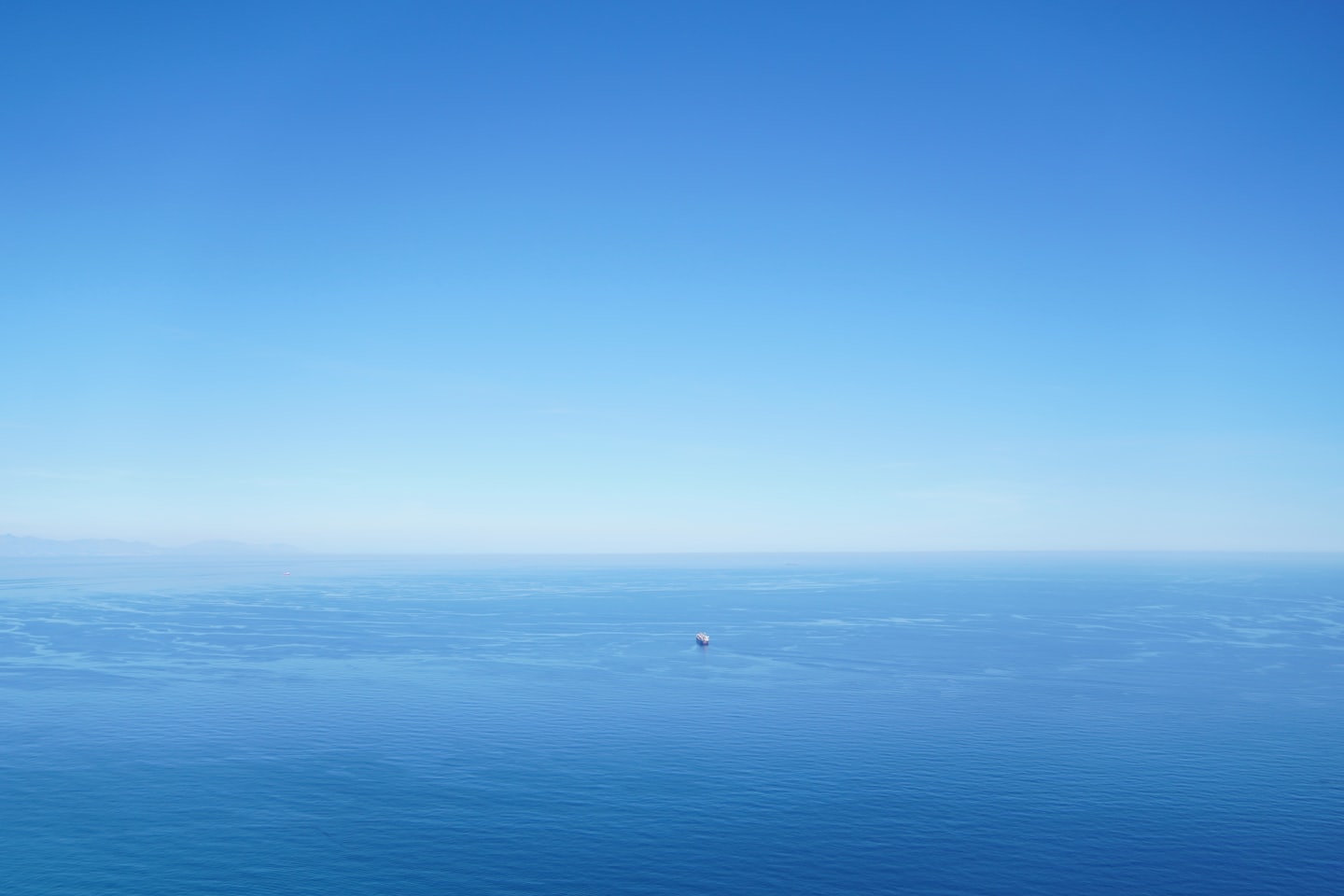 Samotny statek towarowy płynie po spokojnym, błękitnym oceanie.